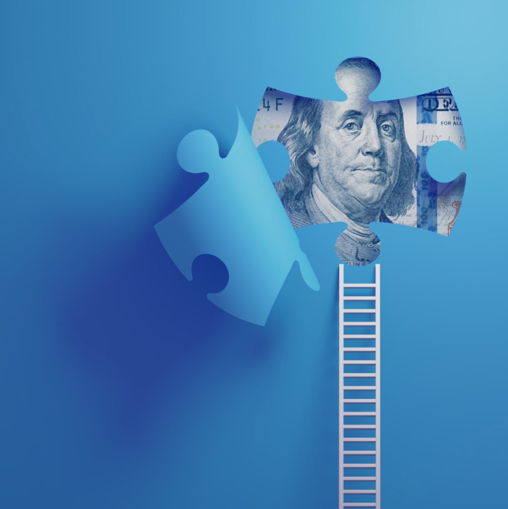 Close-up of a jigsaw puzzle piece featuring Benjamin Franklin’s face from the U.S. $100 bill, placed at the top of a ladder against a blue background. Another puzzle piece is missing on the left side, symbolizing the process of financial or strategic completion.